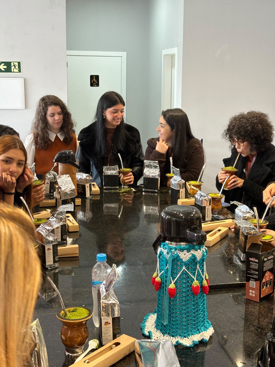 Participantes do encontro em Torres conversando ao redor da mesa com chimarrão